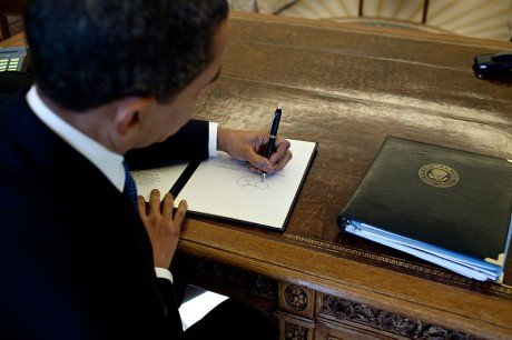 800px Barack Obama signs at his desk