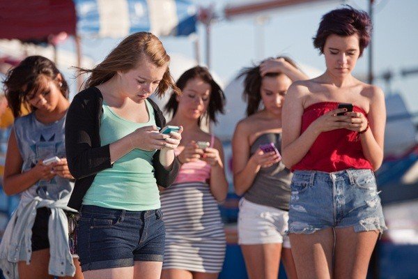Young-women-using-smartphones-at-an-amusement-park